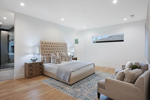 bedroom with light wood-type flooring and connected bathroom