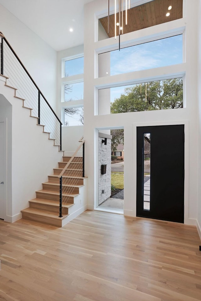 foyer featuring a towering ceiling, a wealth of natural light, and light hardwood / wood-style floors