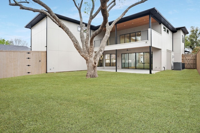 back of property featuring central AC unit, a patio area, a balcony, and a yard