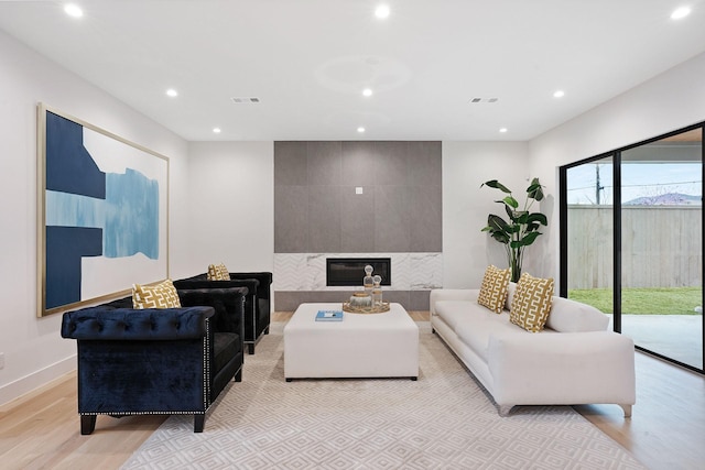 living room with a tiled fireplace and light hardwood / wood-style flooring