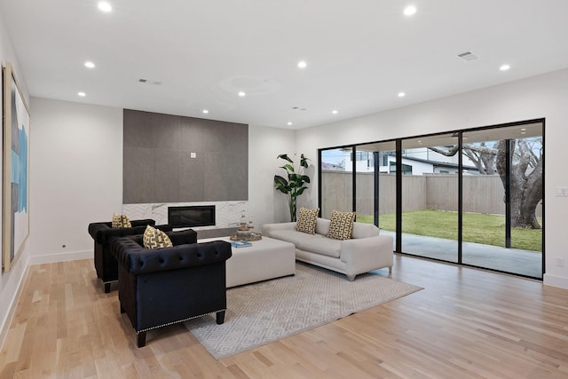 living room featuring a tile fireplace and light hardwood / wood-style flooring