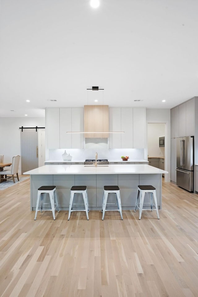 kitchen featuring a kitchen bar, a barn door, a spacious island, and high end fridge