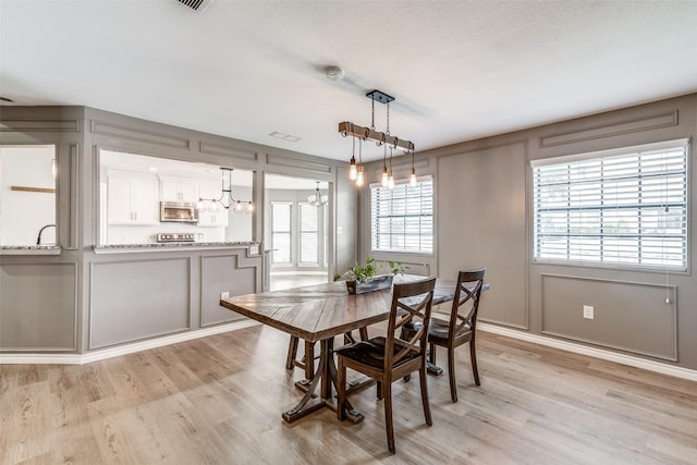 dining space with light hardwood / wood-style flooring and a notable chandelier