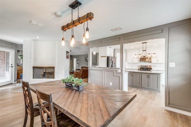 dining space with a fireplace, a notable chandelier, and light hardwood / wood-style flooring