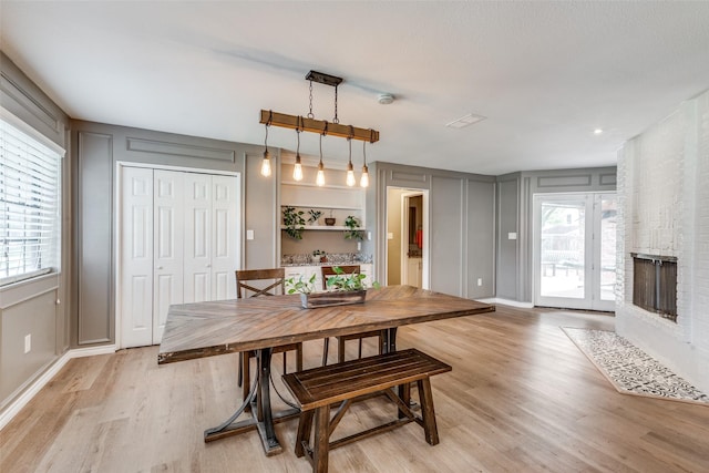 dining room featuring light wood-type flooring and a fireplace