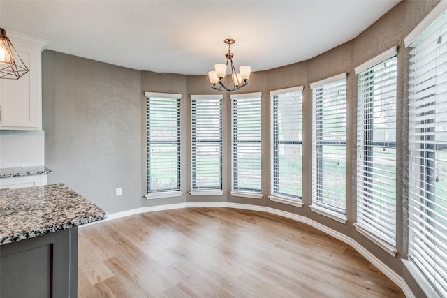 unfurnished dining area featuring light wood-type flooring and an inviting chandelier