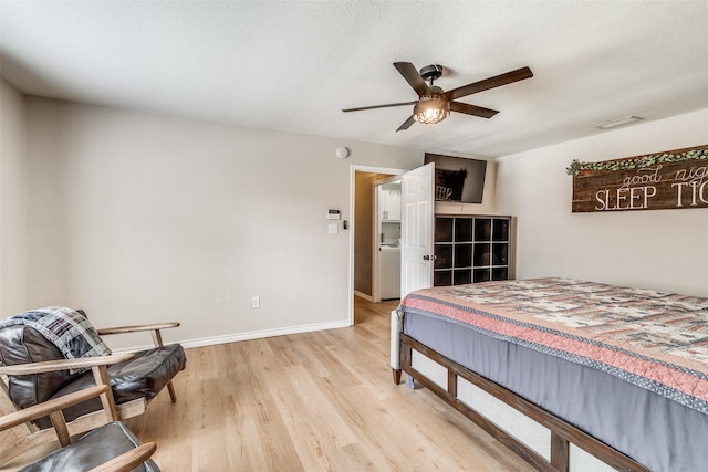 bedroom with ceiling fan, washer / dryer, and light hardwood / wood-style floors