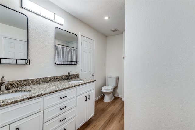 bathroom with toilet, vanity, a textured ceiling, and hardwood / wood-style flooring