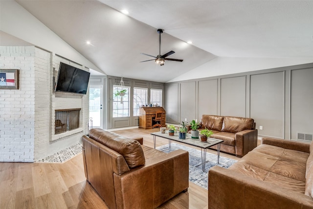 living room with ceiling fan, light hardwood / wood-style flooring, and vaulted ceiling