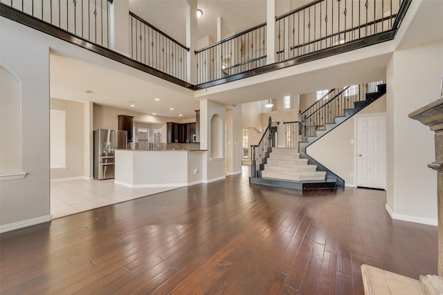 unfurnished living room featuring light hardwood / wood-style floors and a towering ceiling