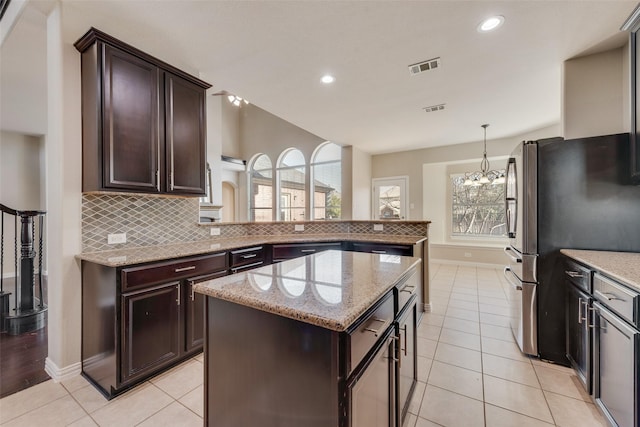 kitchen featuring pendant lighting, a kitchen island, decorative backsplash, kitchen peninsula, and stainless steel refrigerator