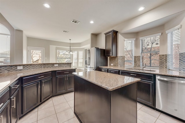 kitchen with pendant lighting, a center island, sink, appliances with stainless steel finishes, and a chandelier