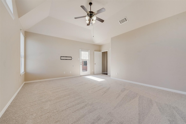 carpeted empty room with ceiling fan, a tray ceiling, and lofted ceiling