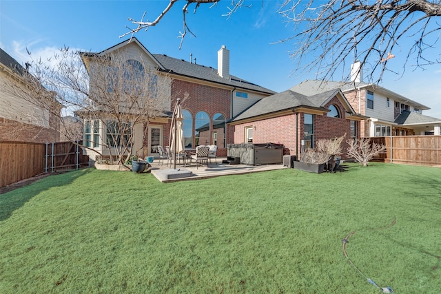 back of property featuring a hot tub, a yard, and a patio