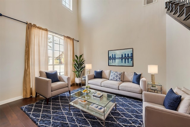 living room featuring dark hardwood / wood-style flooring, a wealth of natural light, and a towering ceiling