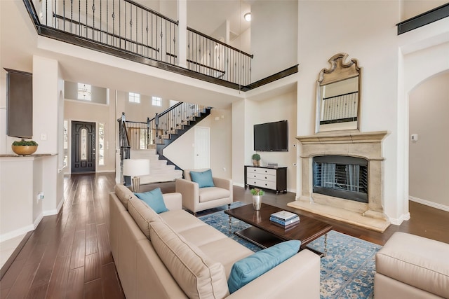 living room with a high end fireplace, dark hardwood / wood-style flooring, and a high ceiling