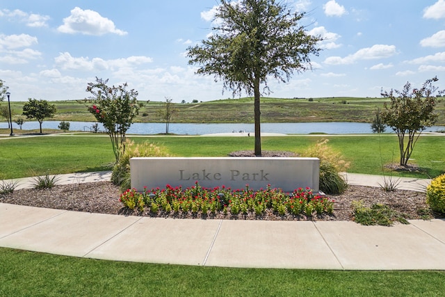 community sign with a water view and a yard