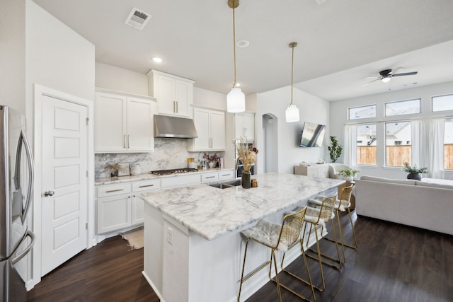 kitchen featuring white cabinetry, appliances with stainless steel finishes, pendant lighting, and an island with sink