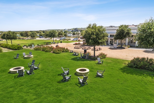 surrounding community featuring an outdoor fire pit and a lawn