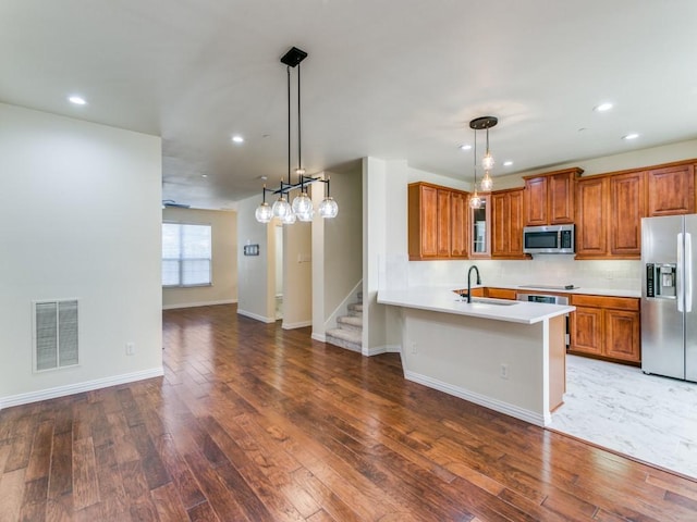 kitchen featuring stainless steel appliances, dark hardwood / wood-style flooring, hanging light fixtures, and sink