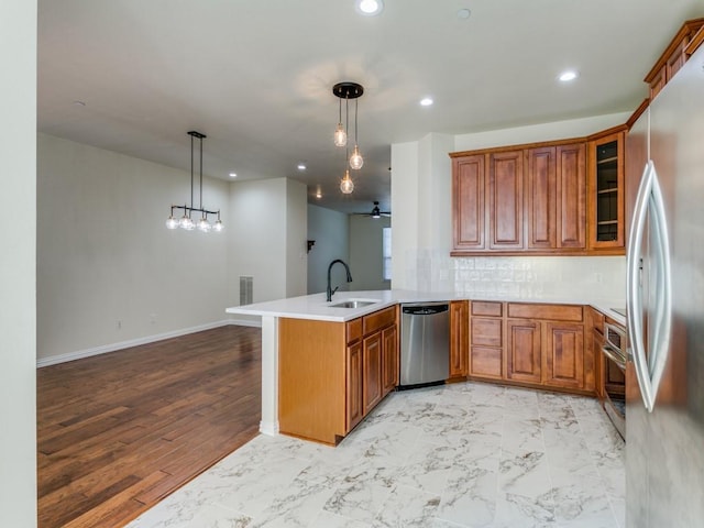 kitchen featuring decorative light fixtures, ceiling fan, kitchen peninsula, sink, and stainless steel appliances