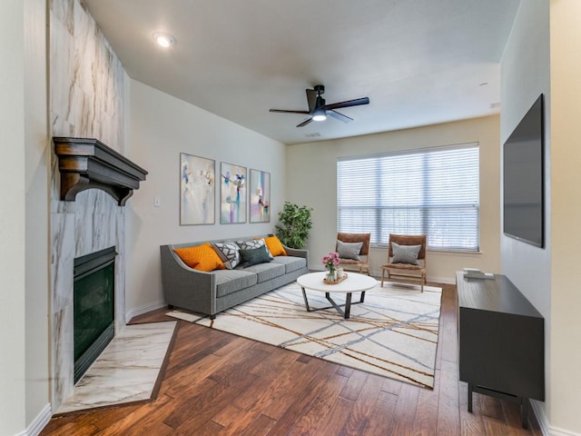 living room featuring ceiling fan, wood-type flooring, and a high end fireplace