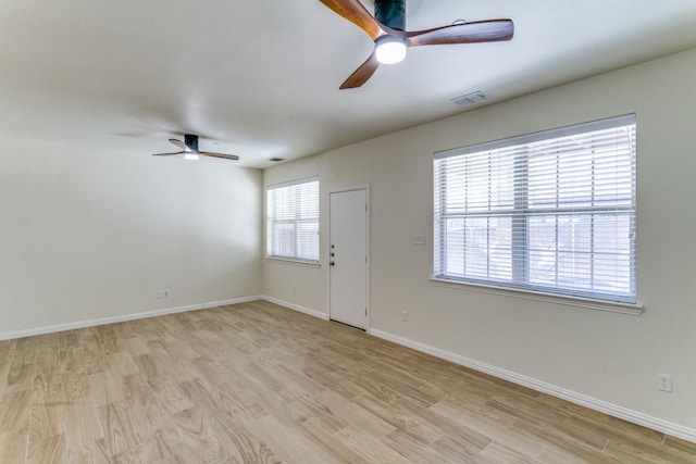 empty room with ceiling fan, a wealth of natural light, and light hardwood / wood-style flooring