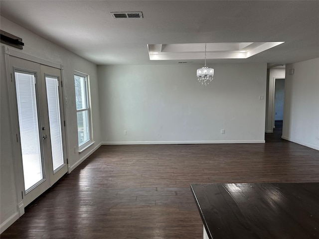 unfurnished room featuring french doors, dark wood-type flooring, plenty of natural light, and a tray ceiling