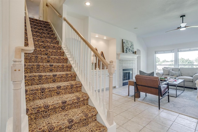 staircase with recessed lighting, a tiled fireplace, vaulted ceiling, ceiling fan, and tile patterned flooring