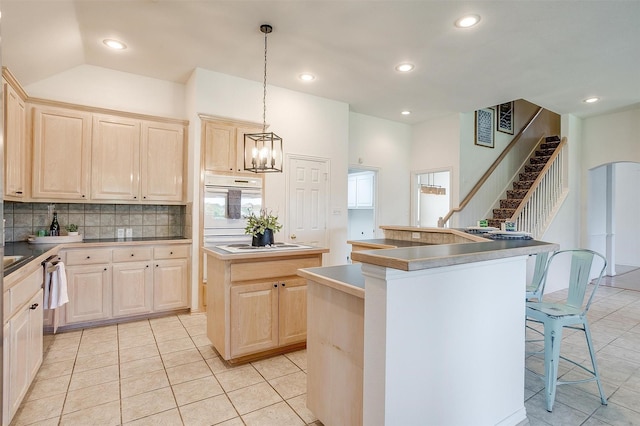 kitchen with white appliances, tasteful backsplash, a kitchen island, and light tile patterned flooring