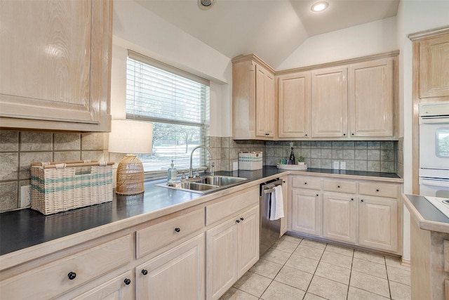 kitchen with dishwasher, lofted ceiling, sink, backsplash, and light tile patterned floors