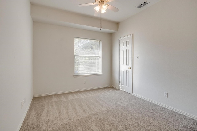 spare room with baseboards, visible vents, ceiling fan, and light colored carpet