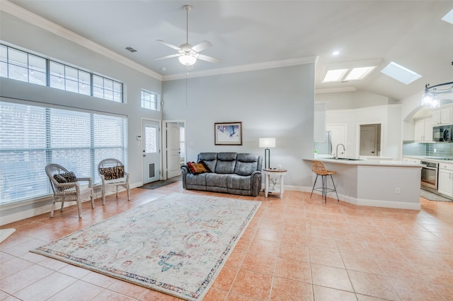 living room with ceiling fan, a wealth of natural light, light tile patterned floors, and crown molding