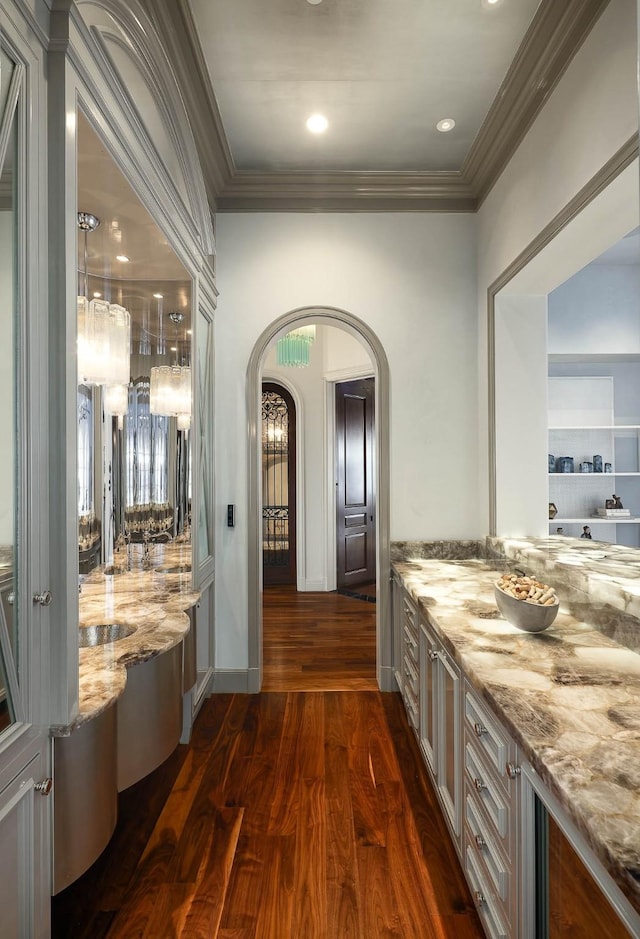 interior space with dark wood-type flooring, light stone countertops, and crown molding