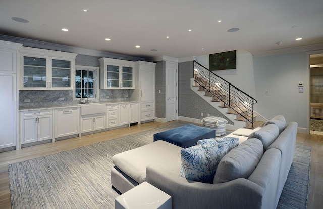 living room featuring light wood-type flooring, sink, and crown molding