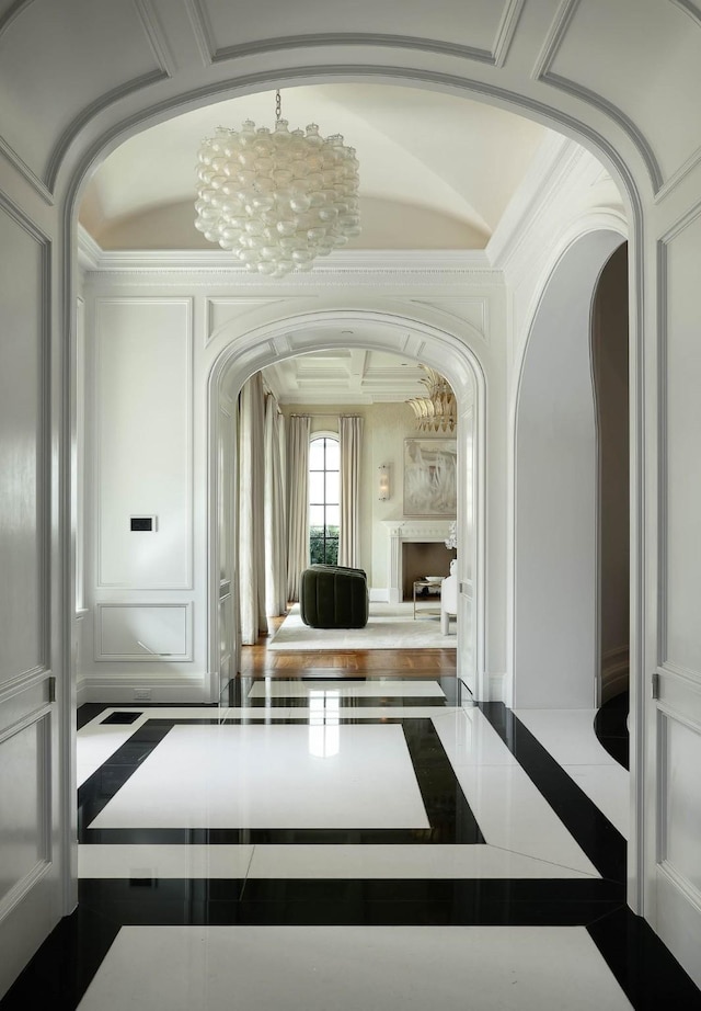 hall with ornamental molding and a notable chandelier