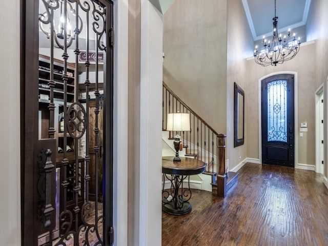 entrance foyer featuring a high ceiling, a chandelier, crown molding, and dark hardwood / wood-style flooring