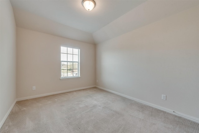 spare room featuring light colored carpet and lofted ceiling