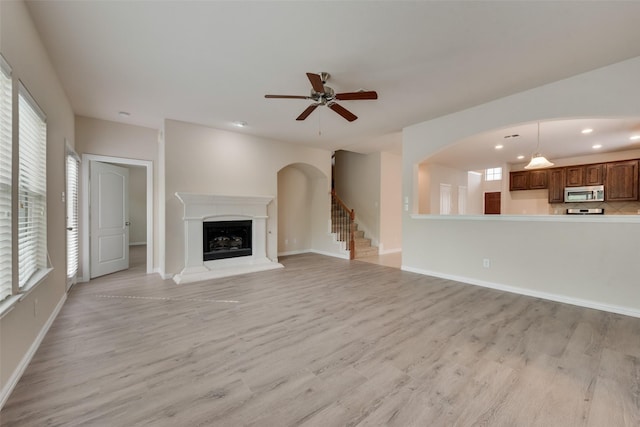 unfurnished living room featuring ceiling fan and light wood-type flooring