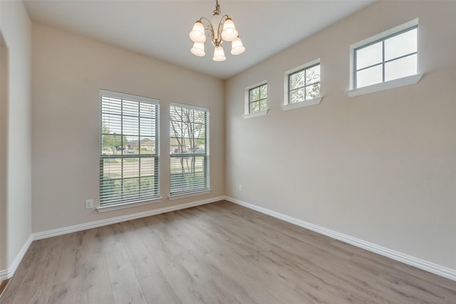 unfurnished room featuring light wood-type flooring and an inviting chandelier