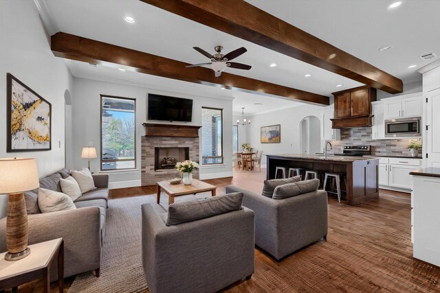 kitchen with white cabinetry, a center island with sink, appliances with stainless steel finishes, a kitchen breakfast bar, and beam ceiling