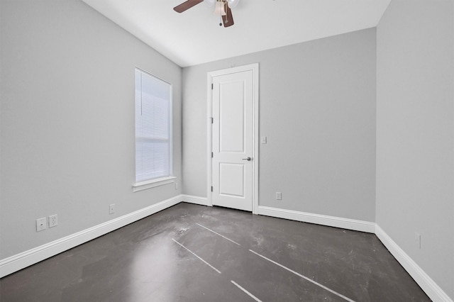 spare room with a ceiling fan, baseboards, and concrete flooring