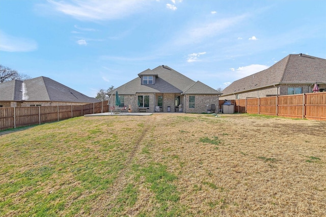 rear view of house featuring a patio, a fenced backyard, an outbuilding, a yard, and a shed