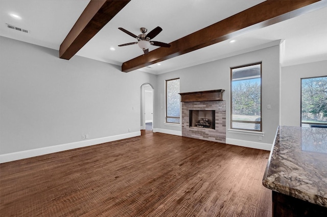 unfurnished living room featuring ceiling fan, dark hardwood / wood-style flooring, and beamed ceiling