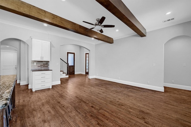 unfurnished living room with baseboards, visible vents, arched walkways, a ceiling fan, and beam ceiling