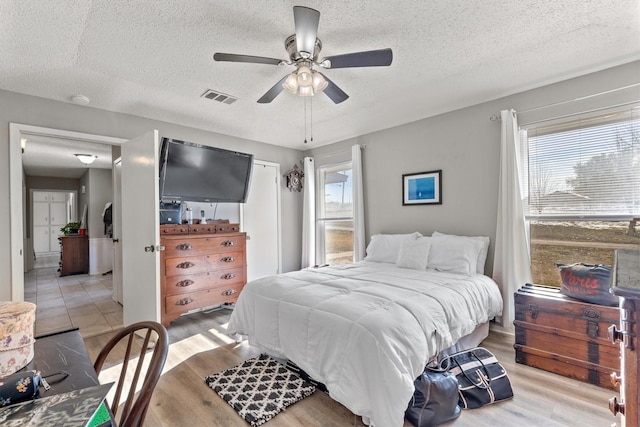 bedroom featuring a textured ceiling, ceiling fan, and light hardwood / wood-style flooring