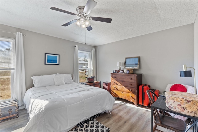 bedroom featuring ceiling fan, a textured ceiling, and light hardwood / wood-style floors