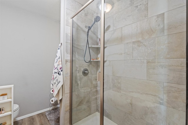 bathroom with toilet, hardwood / wood-style flooring, and a shower with door