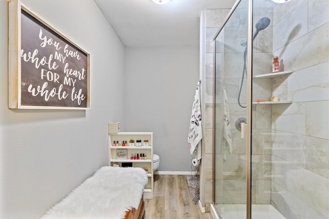 bathroom featuring toilet, a shower with shower door, and hardwood / wood-style flooring