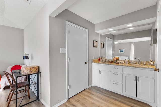 bathroom featuring a textured ceiling, ceiling fan, hardwood / wood-style flooring, and vanity